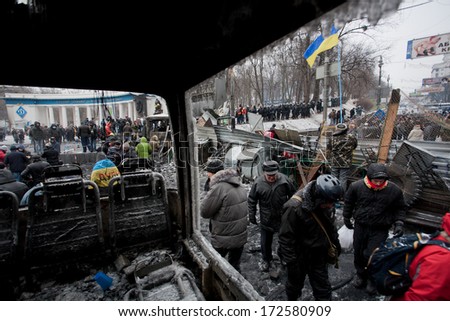 KYIV, UKRAINE - JAN 21: Moving activists walk past the barricades with police squads behind on the occupying snow street during anti-government protest Euromaidan on January 21, 2014, in Kiev, Ukraine