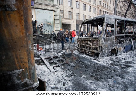 KYIV, UKRAINE - JAN 21: People clean the winter street with ice-covered buses burned in fights with police squads during anti-government protest Euromaidan on January 21, 2014, in Kiev, Ukraine