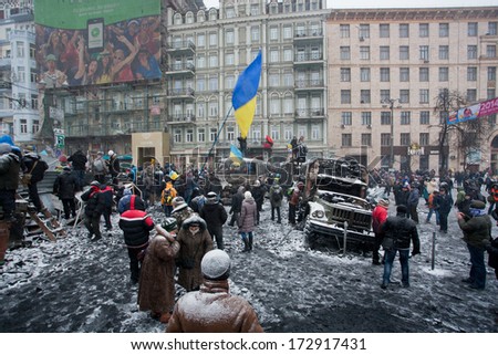 KIEV, UKRAINE - JAN 21: Crowd of people protest with flags on the burned snowy street during long winter anti-government protest Euromaidan on January 21, 2014, in downtown of Kyiv, Ukraine