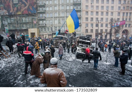 KIEV, UKRAINE - JAN 21: Crowd of active people guard the winter street in city center with burned transport during winter anti-government protest Euromaidan on January 21, 2014, in Kyiv, Ukraine