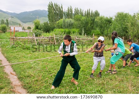 KEMIN, KYRGYZSTAN - AUGUST 2: Children playing tug of rope in the village of Central Asia on August 2, 2013 in Kemin, Kyrgyzstan. Kyrgyzstan\'s population is 5.4 million, 34% are younger age 15 years