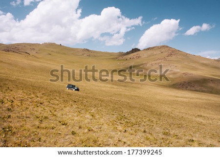 Dry grass hill with auto drive down in the mountains of Central Asia at the bright sunny day