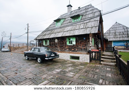 DRVENGRAD, SERBIA - DEC 30: Antique auto parked near traditional wooden house in mystical ethno village on December 30, 2013 in Mecavnic. Drvengrad built by Serbian movie director Emir Kusturica