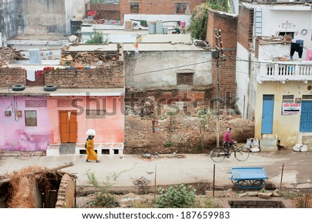 KHAJURAHO, INDIA - DECEMBER 24: People move on the narrow street in poor area of old city with slums & houses on December 24, 2012 in Madhya Pradesh state. Population of Madhya Pradesh is 77 millions