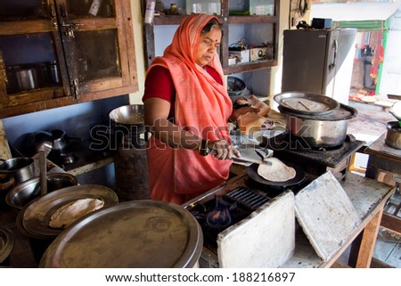 CHITRAKOOT, INDIA - DEC 28: Senior indian lady in sari dress cook national bread in the small street cafe on December 28, 2012. Population of Chitrakoot is 22,294. By the legend, Lord Rama lived here