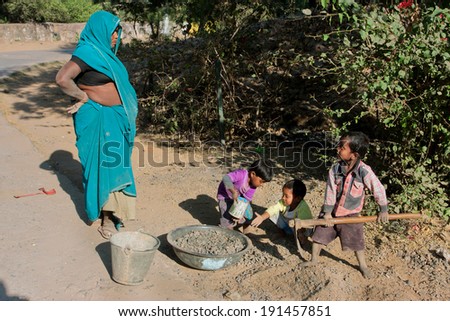 MADHYA PRADESH, INDIA - DEC 22: Unidentified children learn by mother how to repair roads on December 22, 2012. With 75 million people, Madhya Pradesh is the second largest indian state by area