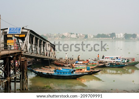 KOLKATA, INDIA - JAN 15: Small colorful riverboats wait for the passengers at river dock on January 15 2013. Third biggest indian city Kolkata with its suburbs is home to approximately 14 mill people