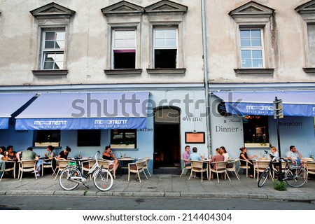 KRAKOW, POLAND - JUL 31: Young people sitting outdoor around the tables of restaurant in old city on July 31 2014. Krakow with popul. of 800,000 people has 2.35 mill. foreign tourists annually