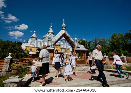 VERKHOVYNA, UKRAINE - AUG 15: Old and young village people walking past the wooden Orthodox church on August 15, 2014. Verkhovyna with pop. 5,500 is located in the Hutsul region of the Carpathian