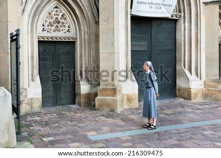 KRAKOW, POLAND - JUL 31: Elderly nun sees the ad on the wall of the Catholic Cathedral on July 31, 2014. Krakow with popul. of 800,000 people has 2.35 mill. foreign tourists annually