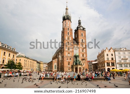 KRAKOW, POLAND - AUG 4: Many people on the square with Church of Our Lady Assumed into Heaven built in 1347 on Aug 4 2014. Krakow with popul. of 800,000 people has 2.35 mill. foreign tourists annually
