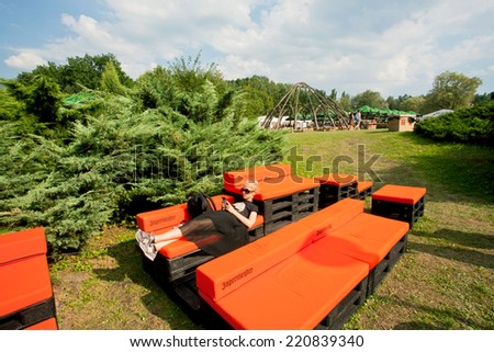 KATOWICE, POLAND - AUG 3: Young girl with mobile phone have rest on the couch on outdoor party on green area of city on August 3, 2014. Katowice lies within an urban zone with population of 2,746,460
