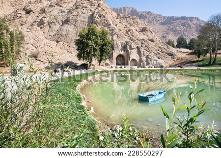 KERMANSHAH, IRAN - OCT 12: Wooden boat in the lake of oasis near the historical landmarks of Taq-e Bostan on October 12, 2014. Taq-e Bostan is large archs with relief from Sassanid Empire of Persia