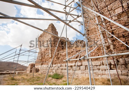 Scaffolding of metal pipes support falling brick wall of an ancient building in the Middle East
