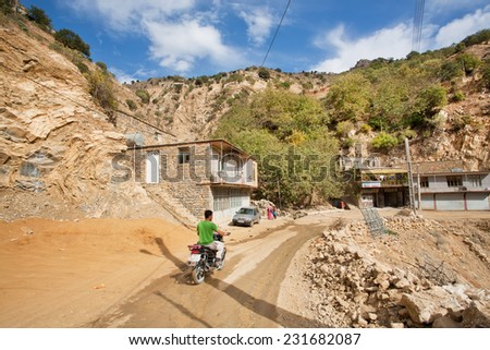 HAWRAMAN-E TAKHT, IRAN - OCT 10: Racer on motorcycle rides through the mountain village on dirt road on October 10, 2014 in Kurdistan. Islamic Republic of Iran is the world\'s 17th most populous nation