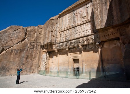 PERSEPOLIS, IRAN - OCT 22: Tourist makes photo of historical landmark - the tomb of persian king Artaxerxes III on October 22, 2014. UNESCO declared citadel of Persepolis a World Heritage Site in 1979
