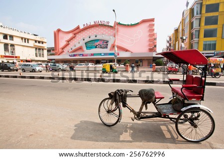 JAIPUR, INDIA - JAN 25: Traditional indian trishaw transport stands past the famous Raj Mandir movie theater on January 25, 2015. Raj Mandir Cinema was designed in Art Moderne style in 1976