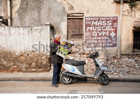 JAIPUR, INDIA - JAN 25: Intelligent man reading the latest news in a newspaper, standing on dirty street of town on January 25, 2015. Jaipur, with population 6,664000 people, is a capital of Rajasthan