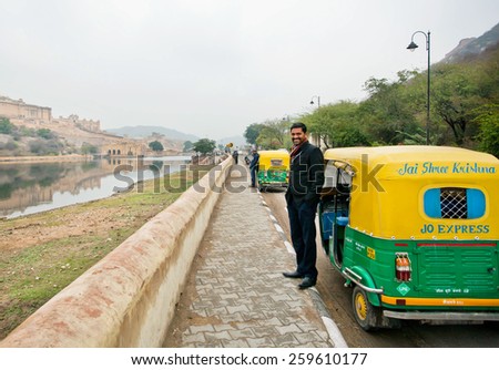 JAIPUR, INDIA - JAN 22: Handsome indian driver stand near the indian moto rickshaw & waiting for the passengers on the road on January, 22 2015. Jaipur, with populat. 6,664000, is capital of Rajasthan