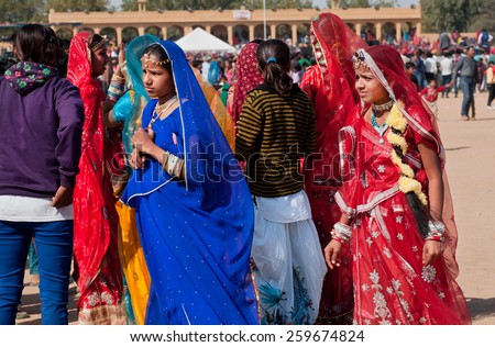 JAISALMER, INDIA - MAR 1: Group of young girls in traditional saris walking on the popular Desert Festival on March 1, 2015. Every winter Jaisalmer takes the famous Desert Festival