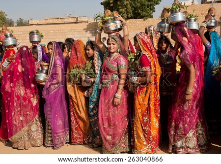 JAISALMER, INDIA - MAR 1: Beautiful dressed women in carry water in jugs and fruits on the famous Desert Festival on March 1, 2015. Every winter Jaisalmer takes the Desert Festival of Rajasthan