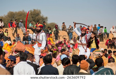 JAISALMER, INDIA - MAR 1: Camel riders with swords happy to see many people in the crowd of the popular Desert Festival on March 1, 2015 in Rajasthan. Every winter Jaisalmer takes the Desert Festival