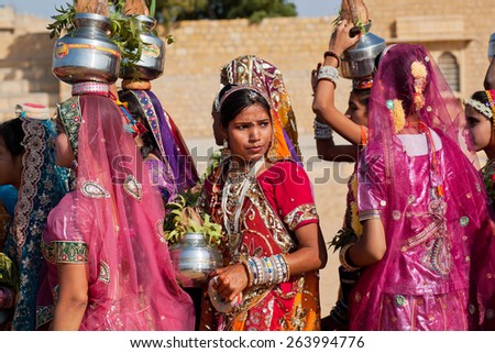 JAISALMER, INDIA - MAR 1: Young woman thinking about something in a crowd of girls dressed in sari on the Desert Festival on March 1, 2015. Every winter Jaisalmer takes Desert Festival of Rajasthan