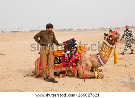 JAISALMER, INDIA - MAR 1: Indian police man holding the camel before the show of the Desert Festival on March 1, 2015 in Rajasthan. Every winter Jaisalmer takes the Desert Festival