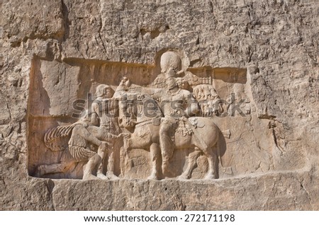 Historical relief carved between 239 - 70 AD about triumph of king Shapur I the Great, Persian rulers. Ancient monuments of Naqsh-e Rustam, rocky necropolis near Persepolis, Iran.