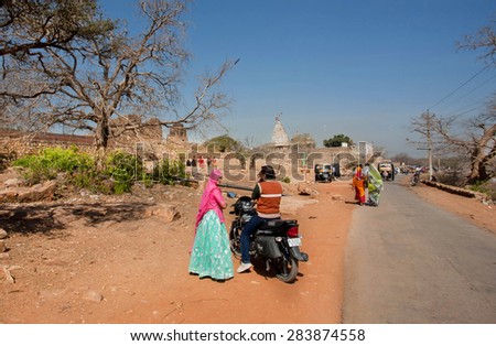 CHITTORGARH, INDIA - FEB 15: Indian couple with motorcycle going on asphalt rural road on February 15, 2015. Chitaurgarh has population about 117,000 and the largest fort in Rajasthan