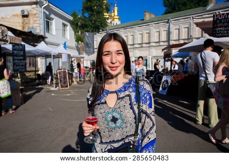 KYIV, UKRAINE - JUNE 6, 2015: Young beautiful lady with glass of wine walking through the stores of Kiev Food & Wine Festival on June 20, 2014. Ukrainian capital, Kiev has population near 2,900,200