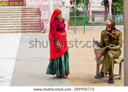 PUSHKAR, INDIA - FEB 9: Indian woman and security officer reading a newspaper outdoor on Fabruary 9, 2015. With population of 15,000 people, Pushkar is a popular touristic town in Ajmer district