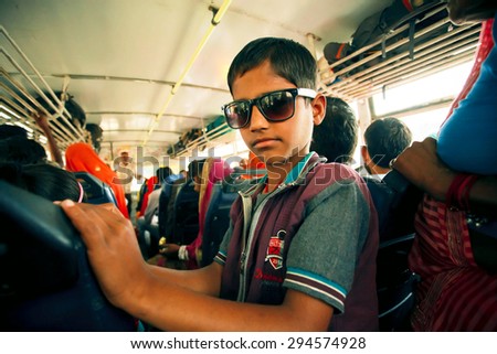 JAIPUR, INDIA - JAN 19: Unidentified kid in sunglasses driving inside a city bus with crowd of passengers on January 19, 2015 in Rajasthan. Jaipur, with popul. 6,664000, is a capital of Rajasthan