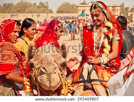 JAISALMER, INDIA - FEB 1: Happy faces of village women in red sari riding the camels during the rural Desert Festival on February 1, 2015. Every winter Jaisalmer takes the famous Desert Festival