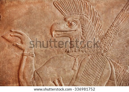 Historical Assyrian relief of bird face genie carrying a cedar-cone, made for Palace at Nimrud in 850BC. Exhibition of artifacts in Pergamon Museum, Berlin.