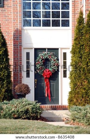 Front door of single family home decorated with wreath and red bow