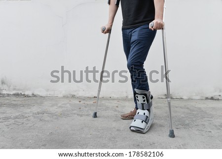 man with broken ankle wearing ankle support with walking crutches