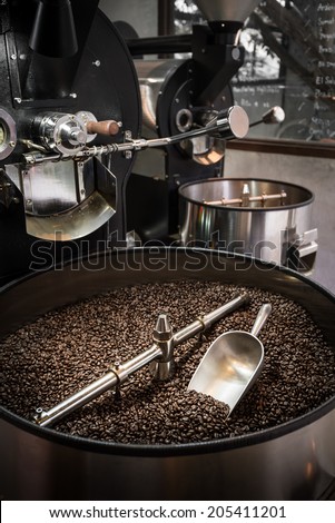 Mixing roasted coffee in roaster cooling container with a scoop