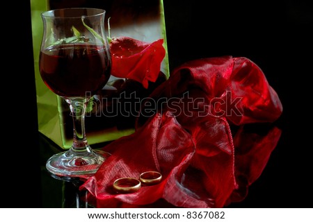 stock photo The gold of wedding ring and red wine on black background