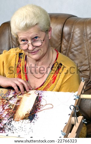 Woman embroidering a picture (cross stitch)
