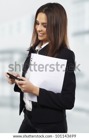 Business woman sending text message on mobile phone at office