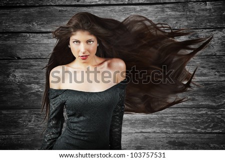 young brunette woman with long flying hair, over wood background