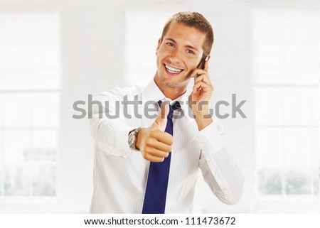 smiling young business man talking on the phone and making ok