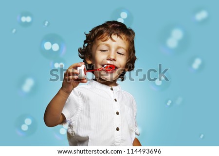 little caucasian boy with soap bubbles on blue background