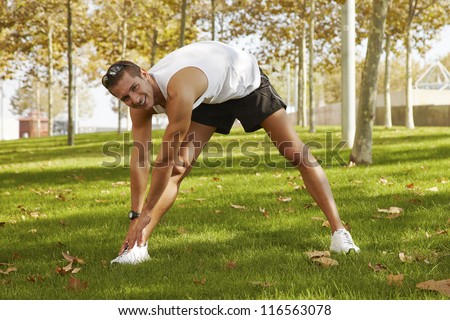 sport man stretching at the park - fitness concepts / Young man sports exercises.