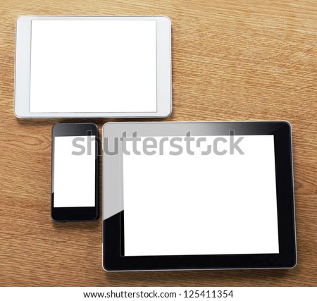 different types of digital tablet and smart phone on a desktop. a mobile phone and a tablets on a table