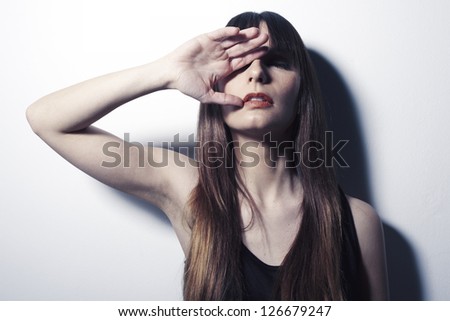 Close up of a young woman covering one eye with her hand. Portrait of a beautiful young woman with sexy lips. Isolated on grey background