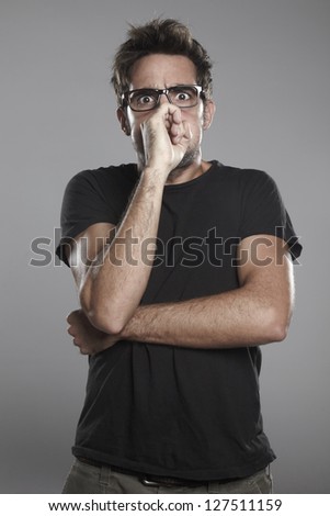 Guy doing gestures. Young man with black glasses on a grey background.