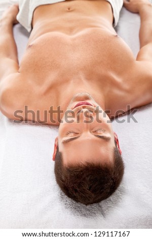 A man relaxed on a stretcher. Isolated on white / A young man is relaxing in spa center