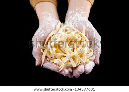 Hands doing fresh italian pasta/ Raw fresh spaghetti isolated on black background